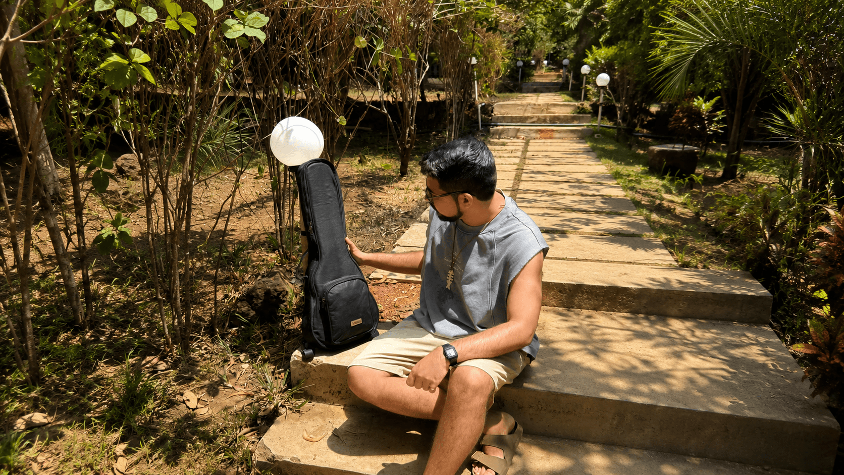 A musician on garden steps with a black Kailo ukulele bag